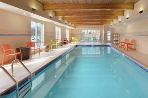 een zwembad in een hotel met oranje stoelen en tafels bij Home2 Suites by Hilton Fort Smith in Fort Smith