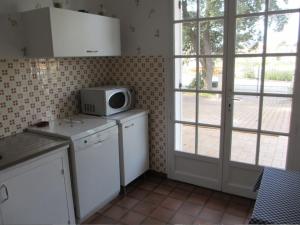 a kitchen with a microwave sitting on top of a counter at Villa proche plage et centre - V06205 in Soulac-sur-Mer +3 photos