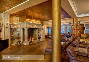 a living room with a fireplace and people sitting on the couch at Lenkerhof gourmet spa resort - Relais & Châteaux in Lenk