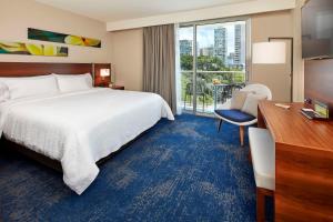 een hotelkamer met een bed, een bureau en een raam bij Hilton Garden Inn Waikiki Beach in Honolulu