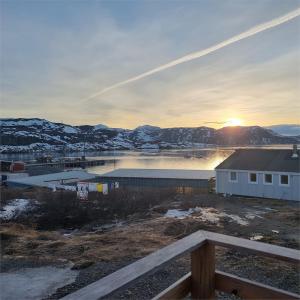 einen Sonnenuntergang über einem Wasserkörper mit einem Gebäude in der Unterkunft Igdlo Guesthouse in Narsaq