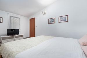 a white bedroom with a bed and a flat screen tv at St. Bečić in Poreč