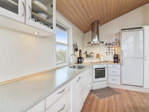 uma cozinha branca com um lavatório e um frigorífico em Holiday Home Florida - 100m from the sea in NW Jutland by Interhome em Lokken