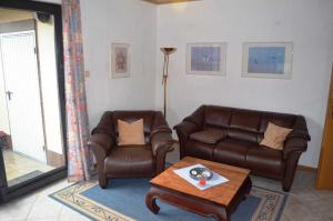 - un salon avec deux fauteuils en cuir et une table basse dans l'établissement Ferienwohnung Gartenweg, à Carolinensiel