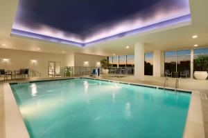 a large swimming pool with blue water in a building at Embassy Suites by Hilton Greenville Downtown Riverplace in Greenville