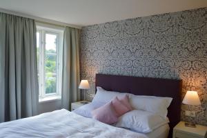 um quarto com uma cama com lençóis brancos e almofadas cor-de-rosa em Rungholt em Oevenum