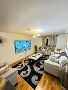 uma sala de estar com 2 sofás e uma televisão de ecrã plano em Whitehouse em Milton Keynes