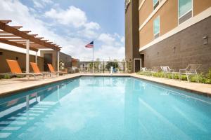 einen Pool in einem Hotel mit Stühlen und einer Flagge in der Unterkunft Home2 Suites by Hilton Houston Webster in Webster