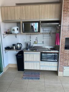 a kitchen with a sink and a microwave at Apartamento confortável em caldas novas com espaço aquático, 6 piscinas , 3 hidromassagem , Bar e Restaurante , Sauna , espaço kids in Caldas Novas