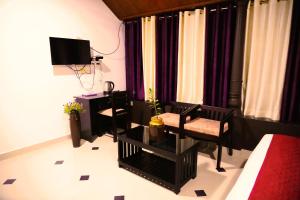 Habitación con cama, escritorio y TV. en Arayathu Heritage Villa Resort, en Kottayam