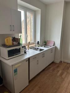a white kitchen with a sink and a microwave at La Douceur - 4 personnes - BCLA in Le Mans