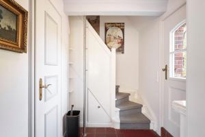 einen Flur mit weißen Wänden und Treppen mit einer Tür in der Unterkunft Sanfte Brise 1- links in Oevenum