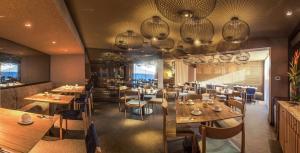 a restaurant with wooden tables and chairs and chandeliers at Doubletree By Hilton Iquitos in Iquitos