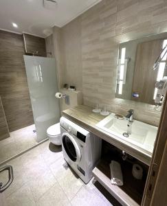 a bathroom with a sink and a washing machine in it at Navarino Luxe Suites in Perea