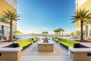 un patio sulla spiaggia con mobili verdi e palme di Hilton Garden Inn Ft. Walton Beach a Fort Walton Beach