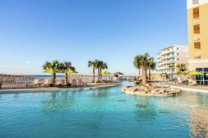 uma piscina com cadeiras e guarda-sóis num resort em Hilton Garden Inn Ft. Walton Beach em Fort Walton Beach