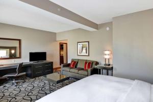 una camera d'albergo con letto, scrivania e divano di DoubleTree by Hilton Hattiesburg, MS a Hattiesburg
