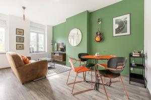 a living room with green walls and a table and chairs at La Maison Jaurès - Le Larsen in Liévin