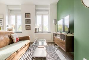 sala de estar con sofá y TV de pantalla plana en Le Larsen, en Liévin