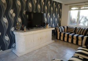 a living room with a flat screen tv and two couches at Cosy Stirling 3-bedroom Home in Stirling