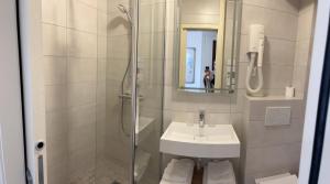 a bathroom with a shower and a sink and a mirror at Logis Hôtel des Messageries in Arbois
