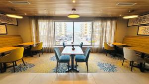 ドバイにあるHampton By Hilton Dubai Al Barshaのテーブルと椅子、大きな窓のあるレストラン