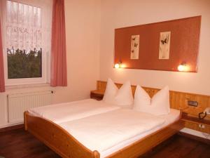Schlafzimmer mit einem Bett mit weißer Bettwäsche und einem Fenster in der Unterkunft Pension Haus Flora in Oberhof