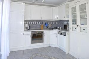 a white kitchen with white cabinets and appliances at Seedüne in Wyk auf Föhr