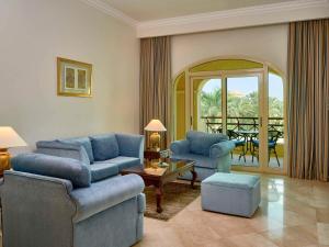 a living room with two blue chairs and a table at Mövenpick Hotel Cairo - Media City in 6th Of October