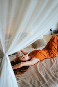 a woman in an orange dress laying on a bed at Casa de Areia in Jericoacoara
