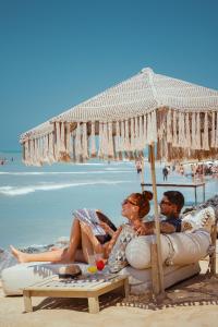 duas pessoas sentadas debaixo de um guarda-sol na praia em Casa de Areia em Jericoacoara