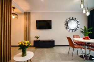 ザジェチェにあるLaguna Beskidów Resort - Apartament A59のテーブルと壁にテレビが置かれたリビングルーム