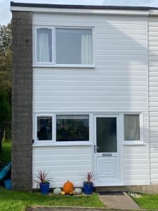 a white house with windows and pumpkins in front of it at Beach Woods Coastal Path chalet in Pembrokeshire