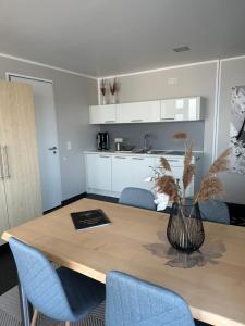 a dining room table with blue chairs and a kitchen at Open-Water-Resort in Geierswalde