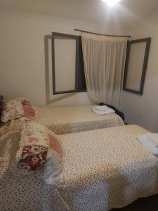 um quarto com uma cama com um edredão e 2 janelas em Doslilas em Guaymallén
