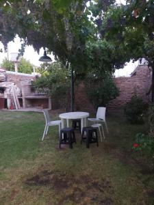 uma mesa e cadeiras na relva debaixo de uma árvore em Doslilas em Guaymallén