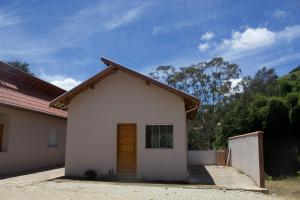 ein kleines weißes Haus mit einer Holztür in der Unterkunft Chales Maria Flor in Gonçalves