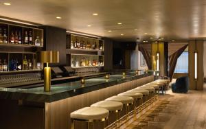 a bar with a row of stools in a room at The Time New York, part of JdV by Hyatt in New York