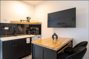 uma cozinha com armários pretos, um lavatório e uma televisão em eve's room em Haifa