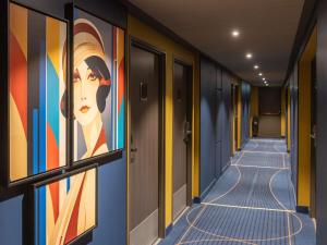 a corridor with paintings of a woman on the wall at ibis Styles Saint-Quentin in Saint-Quentin
