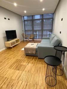 Apartamento en Casco Vello Vigo في فيغو: غرفة معيشة مع أريكة وطاولتين