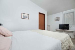 a white bedroom with a bed and a television at Apartment in Mugeba/Istrien 27611 in Mugeba
