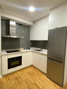 Apartamento en Casco Vello Vigo في فيغو: مطبخ مع دواليب بيضاء وثلاجة ستانلس ستيل