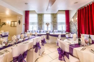 a banquet hall with white tables and purple bows at Cambridge Hotel Waterfront in Brighouse