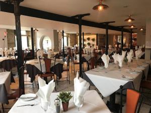 uma sala de jantar com mesas e cadeiras brancas em Cambridge Hotel Waterfront em Brighouse