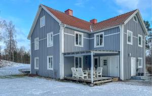 een grijs huis met twee witte stoelen op de veranda bij Gorgeous Apartment In Vrnamo With Kitchen in Förhult