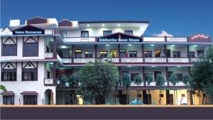 un grand bâtiment blanc avec des personnes sur les balcons dans l'établissement Siddhartha Guest House, à Rummindei