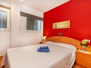 a red bedroom with a bed with a blue bag on it at Apartment Codolar by Interhome in Tossa de Mar