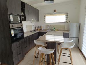 a kitchen with wooden cabinets and a counter with white stools at Refugio las Quemas in Futrono