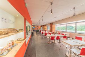 里昂Residence Montempo Lyon Cite Internationale的有桌子和红色椅子的餐厅